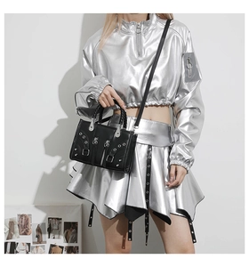 Detailed view of punk style black leather handbag with silver studs and braided handle