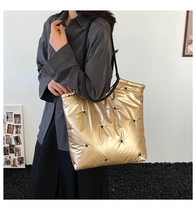 Detail of metallic gold quilted tote bag featuring black stars and long shoulder straps