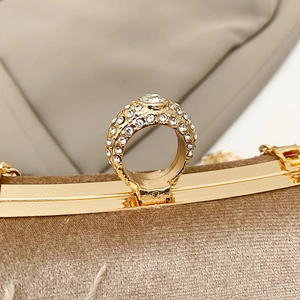 Macro detail of gold finger-ring clasp with sparkling crystals on suede clutch bag