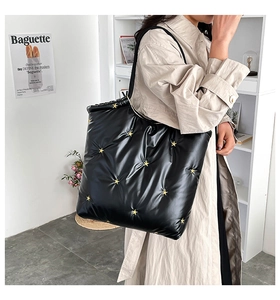 Close-up of quilted black tote bag with gold star accents and soft padded texture