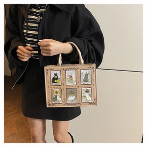 Detail of light brown tote bag featuring artistic cat tarot card prints and metal rivets
