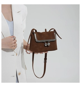 Detail of dark brown retro shell bag with silver ball clasp and adjustable strap
