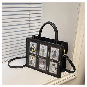 Detail of black tote bag featuring cat tarot card illustrations and gold studs decoration