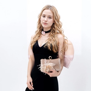 Close-up of champagne velvet evening bag with 3D floral sequins and feather details