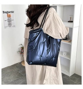 Quilted blue tote bag with star embroidery and metallic finish carried by a model