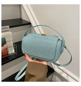 Close-up of light blue glitter box bag with gold metal clasp and top handle