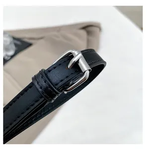 Detail of adjustable black leather shoulder strap with a silver metal buckle closure
