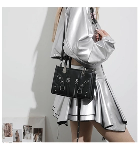 Detail of black punk leather tote bag with silver metal eyelets and zipper accents