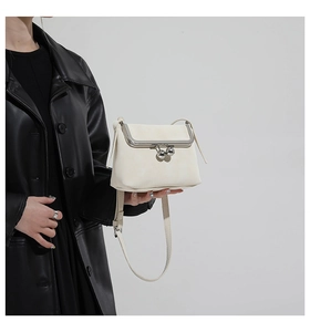 Close-up of white leather handbag featuring a vintage silver metal ball clasp closure