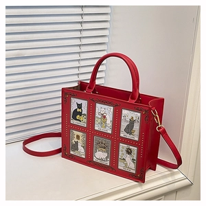Close-up of red tote bag featuring cat tarot card illustrations and gold stud details