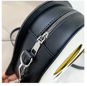 Close-up of smooth silver zipper and textured PU leather on a black and white bag