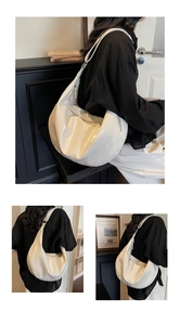 Detail of white glossy patent leather half-moon shoulder bag with sleek metal zipper