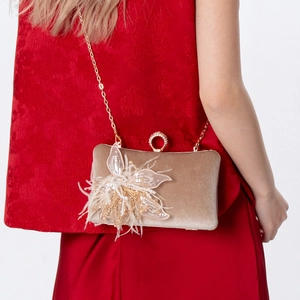 Close-up of champagne gold velvet evening clutch with handmade floral sequins and pearls
