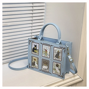 Detail of light blue tote featuring cat tarot illustrations and golden stud accents
