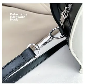 Detailed shot of detachable silver metal hooks on the black and white shoulder bag