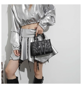 Detail of black punk style leather handbag with metal zippers and grommet accents