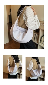 Detail of light purple glossy crescent shoulder bag showing shiny texture and strap