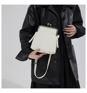 Detail of cream-white pebble grain leather surface and vintage silver metal clasp closure