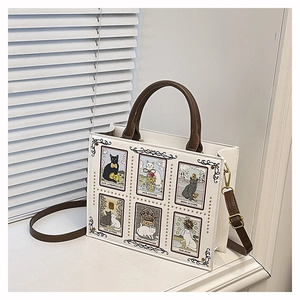 Close-up of cat tarot card prints and gold rivet details on white leather tote bag