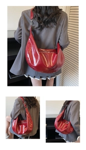 Detail of red glossy hobo bag with silver zipper and wide adjustable shoulder strap