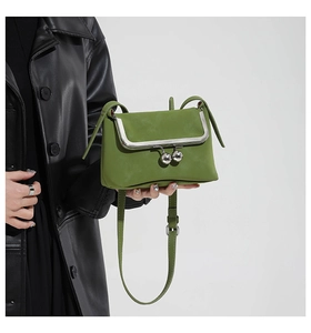 Close-up of retro green leather satchel with silver metal clasp held by a model