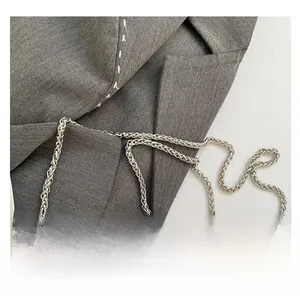 Detail of silver woven metal chain strap with vintage embossed circular medal emblem