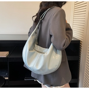 Detail of mint green crescent bag in glossy patent leather with stylish ruching effect
