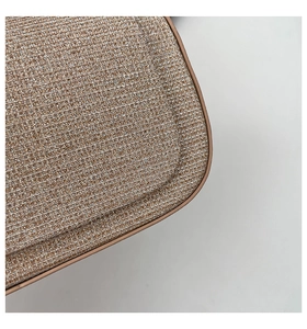 Close-up of glitter woven fabric and smooth brown trim on a luxury box handbag