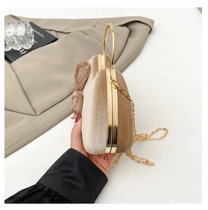 Detail of champagne velvet clutch featuring elegant 3D floral accent and gold ring handle