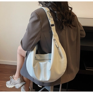 Detailed back view of a light blue patent leather hobo bag worn with a brown blazer