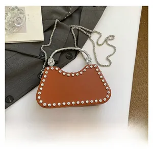 Brown box bag with silver studs and metal handle shown with phone for size reference