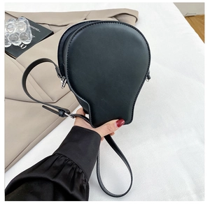 Detail of unique skull-shaped black matte crossbody bag held in hand for scale