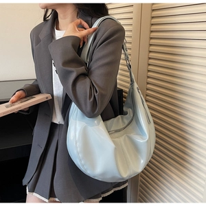 Close-up of light blue shiny leather hobo bag with zip closure and stitching detail
