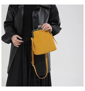 Detail of a vintage ginger yellow kiss-lock crossbody bag worn with a black leather coat