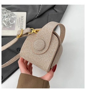 Detailed close-up of woven metallic gold mini crossbody bag with round buckle detail