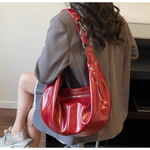 Detail of burgundy glossy patent leather hobo bag with wide shoulder strap and zipper