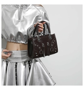 Detail of dark brown leather handbag featuring silver metal rivets and braided handles