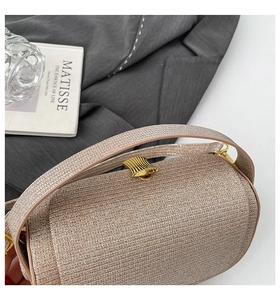 Close-up of champagne gold woven evening clutch featuring an elegant wavy metal clasp