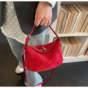 Close-up of vibrant red suede hobo bag featuring a sleek silver twist-lock and fine texture