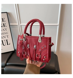 Detail of woven handles and silver studs on a dark red leather motorcycle handbag