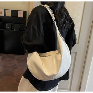 Detail of white glossy hobo bag with adjustable wide shoulder strap and silver hardware