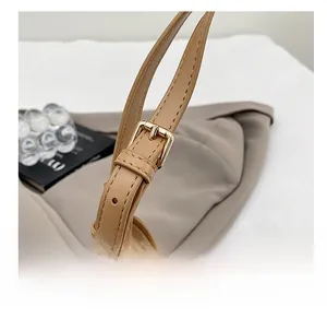 Gros plan sur la boucle dorée réglable et les coutures de la bandoulière en cuir kaki