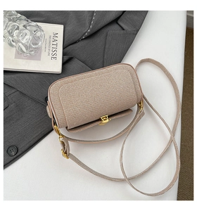 Detail of woven texture flap bag with polished gold clasp and slim shoulder strap