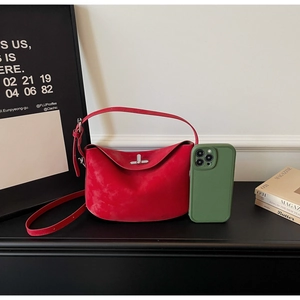 Close-up of red suede handbag with silver metal buckle and green phone for size reference