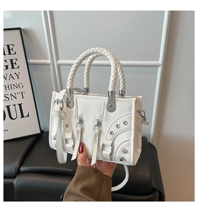 Detail of white leather shoulder bag with vintage silver rivets and woven handle