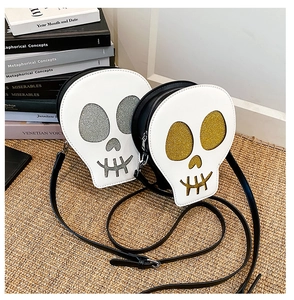 Detail of creative skull-shaped crossbody bags in silver and gold sequins on woven mat