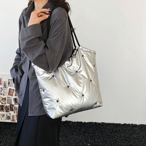 Silver quilted down tote bag with black star embroidery shown on a female model