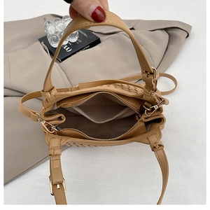 Détail du sac tissé beige montrant la poche zippée intérieure et les ferrures métalliques