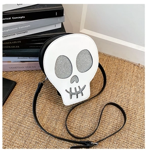 Detailed view of skull-shaped crossbody bag with glitter accents on woven mat