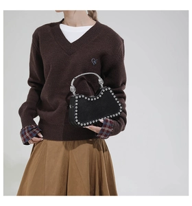 Detail of a vintage-style black box bag featuring silver rivets and a metal curved handle